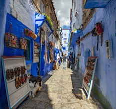 Sale of leather sandals in narrow lane with blue houses