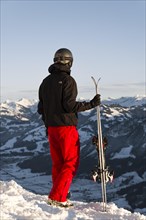 Skier stands at the piste and holds ski