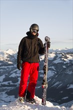 Skier stands at the piste and holds ski