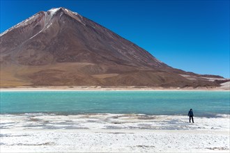 Laguna verde with deposits of borax on the shore and snow on the mountains
