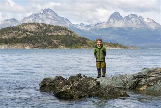 Little boy standing on rocks on the banks of the Beagle Channel