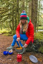 Young woman cooking outdoors with camping stove
