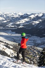 Female skier with ski helmet on the ski slope above the valley
