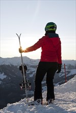 Female skier with ski helmet standing with ski at the ski slope