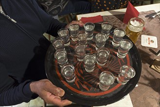 Waiter with tray of filled schnapps glasses in an inn