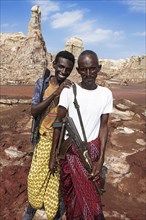 Armed Afar nomads with Kalashnikov in the rocky landscape at the edge of Lake Karum