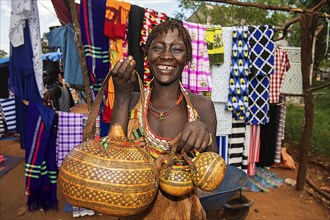 Laughing woman of the Hamer ethnic group sells artfully decorated calabashe pumpkins
