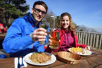 Hikers enjoying a hearty snack with Palatinate Saumagen and sausage salad in front of the Kalmithaus on the summit of Kalmit