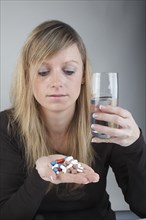 Young woman holding a large amount of pills in her hand