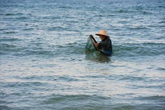 Crabfisher with straw hat in the water