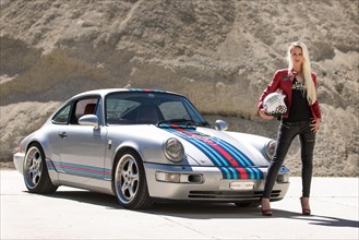 Young woman with long blonde hair poses with Porsche 911 Carrera 4