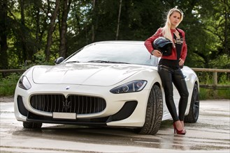 Young woman with long blond hair poses with white Maserati Gran Turismo MC Stradale