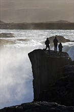 Silhouette of three tourists on a rock