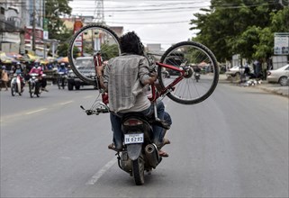Man with moped carries a bicycle