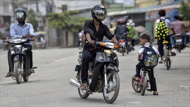 Mopeds and child with bike on the road