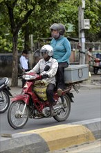 Man on moped and woman sitting on a box