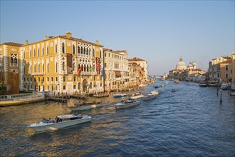 Water taxis and vaporettos on Grand Canal with Renaissance architectural style palace buildings in San Marco and Santa Maria della Salute basilica in Dorsoduro