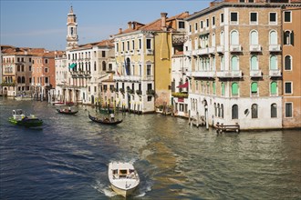 Water taxi and gondolas on Grand Canal lined with Renaissance architectural style residential palace buildings