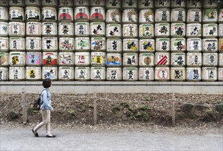 Woman walks pass sake barrels at Meiji Jingu Shrine