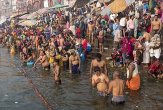 Hindu believers bath and perform ritual bath and puja prayers at ghats in the River Ganges