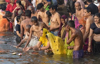 Hindu believers bath and perform ritual bath and puja prayers at ghats in the River Ganges