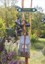 Sign Malerweg hiking trail with hiking boots and backpack in Daube near Lohmen