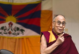 Dalai Llama speaks in front of Tibet flag