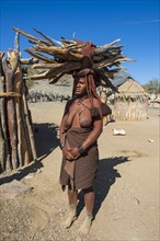 Himba woman carrying wood on her head