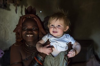 Himba woman holding a white tourist baby