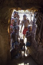 Many curious children looking in a Himba hut