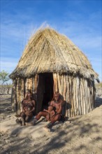 Himba women in front of their wooden hut