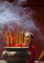 Young woman with burning incense sticks on Chinese New Year