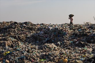 Garbage collector in garbage dump with plastic garbage