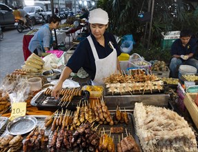 Seller with meat skewers and sausage skewers at the market