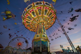 Rotating chain carousel and ferris wheel at the blue hour