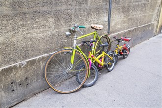 Bicycles for adult and children parked against wall
