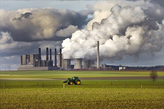 Tractor on a field in front of the steaming lignite-fired power station Frimmersdorf