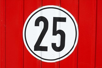 Road sign speed limit 25 Km/h on red wood wall