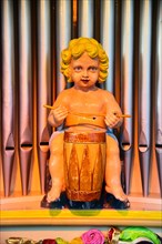 Drummer figure in front of organ pipes