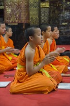 Buddhist monks praying in the temple Wat Xieng Thong