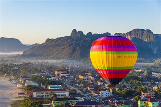Colorful hot air balloon drifts over the city