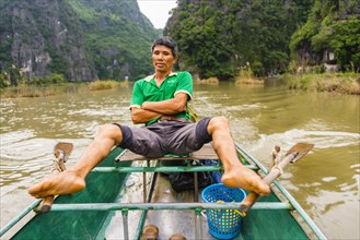 Local man rowing with his feet on the Ngo Dong River