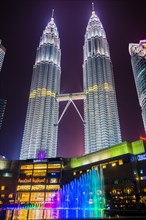 Lighted Petronas Towers with multicolored fountain at night