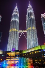 Lighted Petronas Towers with colored fountain at night