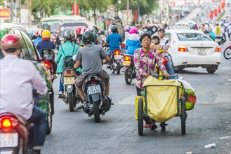 Woman pushing cart through scooter riders in heavy traffic