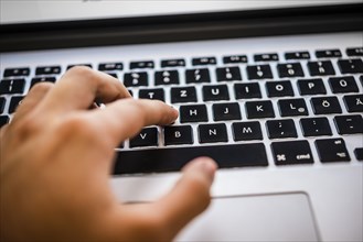 Hand typing on MacBook Pro keyboard