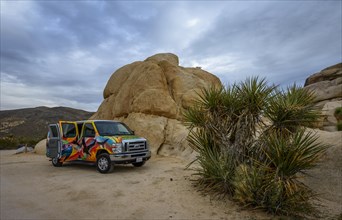 Colorful camper van in front of large granite rock
