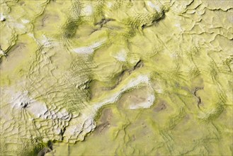 Water flowing over rocks with sulfur deposits