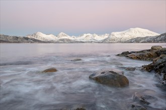 Coast in evening light and snow covered mountains