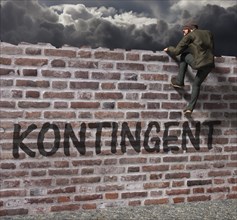 Man climbing over a wall with writing contingent
